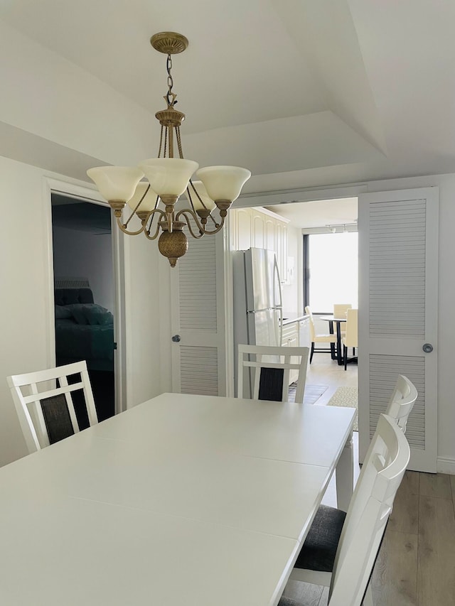 dining space with light hardwood / wood-style floors and an inviting chandelier