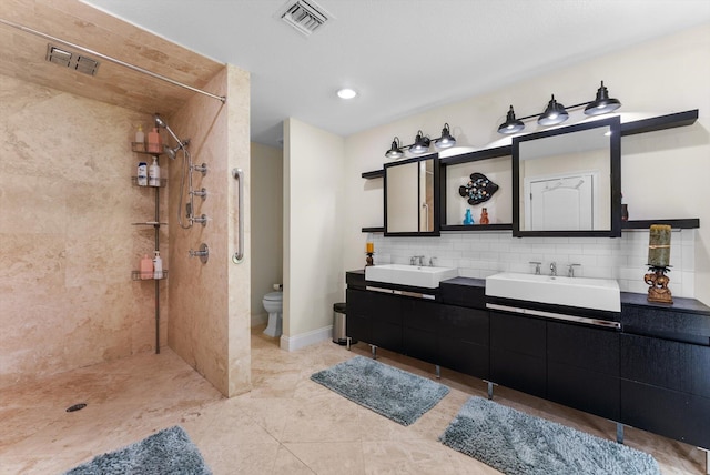 bathroom featuring tiled shower, vanity, backsplash, and toilet