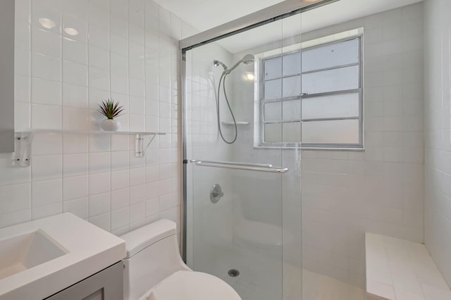 bathroom featuring vanity, toilet, a shower with shower door, and tile walls