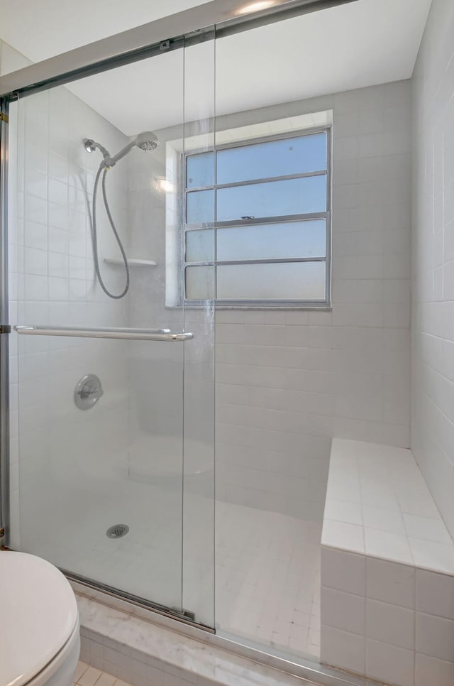 bathroom featuring tile patterned floors, toilet, and a shower with door