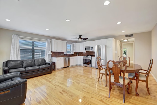 living room with ceiling fan, sink, and light wood-type flooring