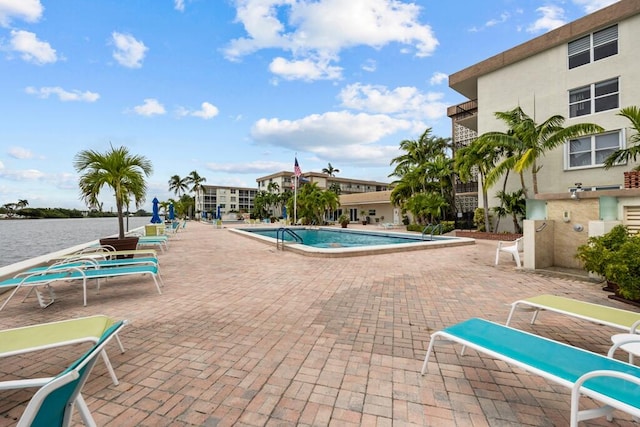 view of swimming pool with a water view and a patio area