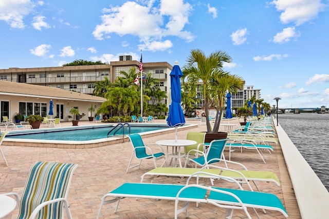 view of pool featuring a water view and a patio