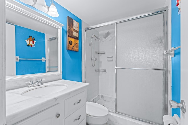 bathroom featuring tile patterned floors, vanity, toilet, and an enclosed shower