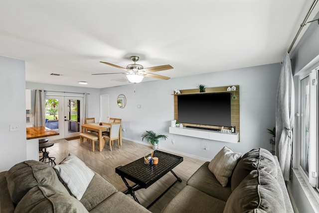 living room with ceiling fan, french doors, and light hardwood / wood-style flooring