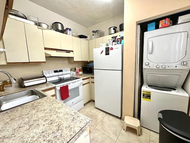 kitchen with stacked washing maching and dryer, a textured ceiling, white appliances, sink, and cream cabinetry