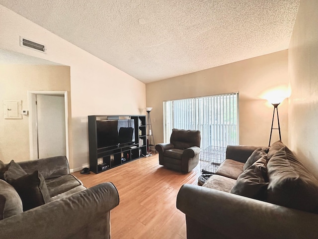 living room with hardwood / wood-style floors, a textured ceiling, and lofted ceiling