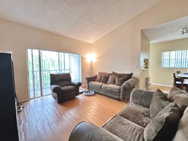 living room with vaulted ceiling, a textured ceiling, and hardwood / wood-style flooring