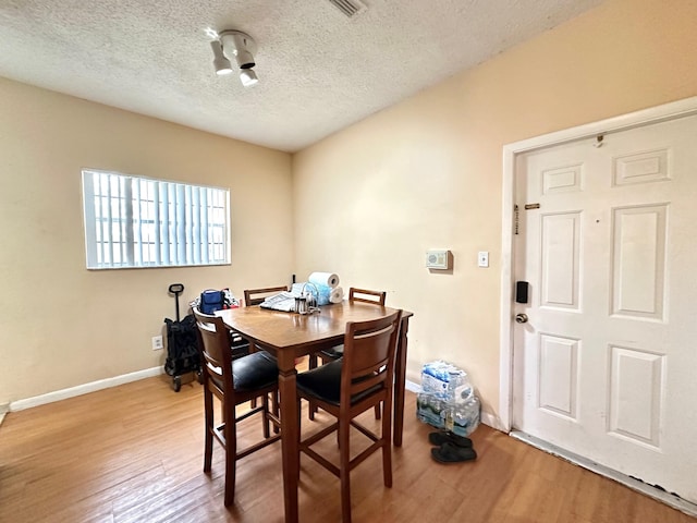 dining area with light hardwood / wood-style floors and a textured ceiling