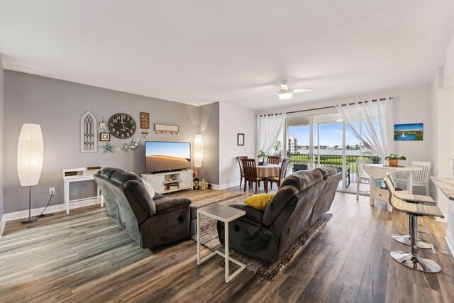 living room featuring wood finished floors, a ceiling fan, and baseboards