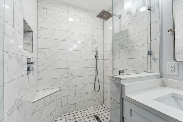 full bathroom with a tile shower and vanity