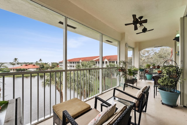 sunroom featuring a water view and ceiling fan