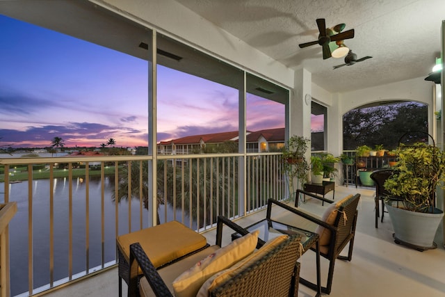 sunroom / solarium featuring ceiling fan and a water view