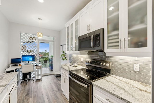 kitchen with wood finished floors, white cabinets, appliances with stainless steel finishes, light stone countertops, and tasteful backsplash