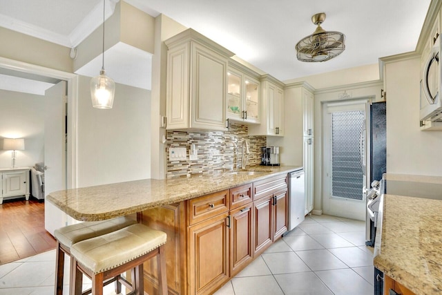 kitchen with a kitchen breakfast bar, stainless steel dishwasher, sink, decorative light fixtures, and light hardwood / wood-style flooring