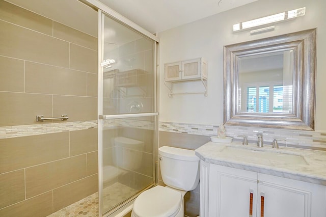 bathroom with backsplash, an enclosed shower, toilet, vanity, and tile walls