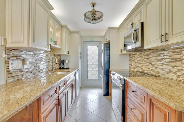 kitchen with tasteful backsplash, cream cabinets, sink, and stainless steel appliances