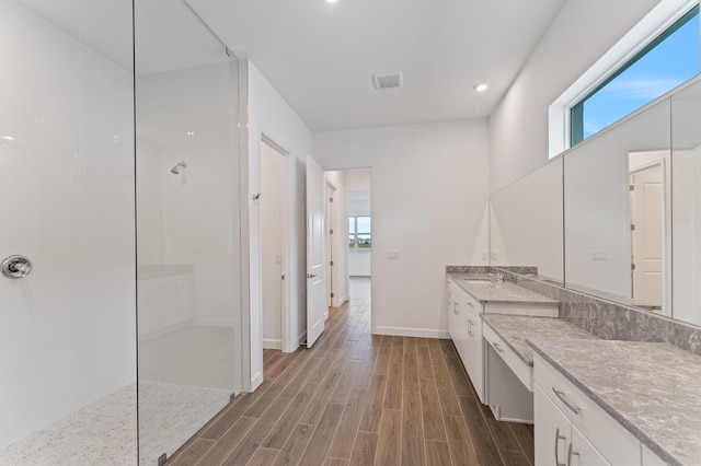 bathroom with a tile shower and vanity