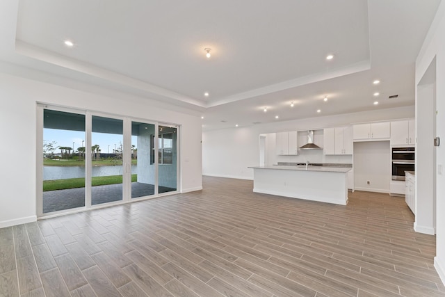 unfurnished living room with a tray ceiling and a water view