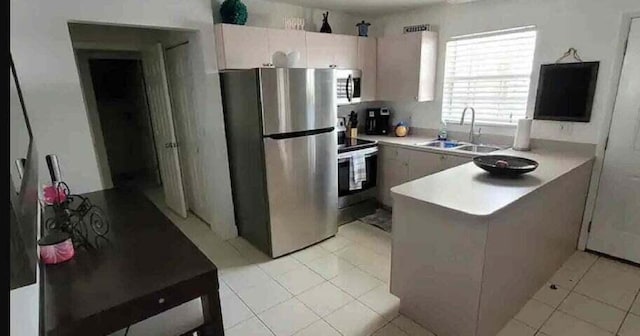 kitchen featuring sink, kitchen peninsula, stainless steel appliances, and light tile patterned floors