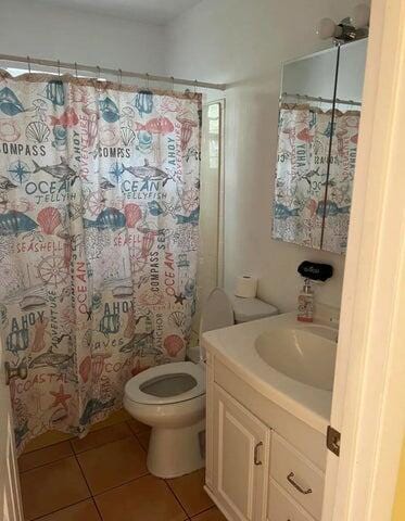 bathroom featuring tile patterned floors, vanity, curtained shower, and toilet