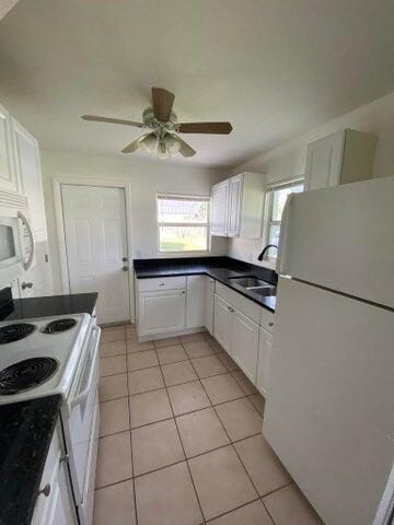 kitchen with white appliances, ceiling fan, sink, light tile patterned floors, and white cabinets