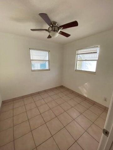 tiled spare room featuring ceiling fan