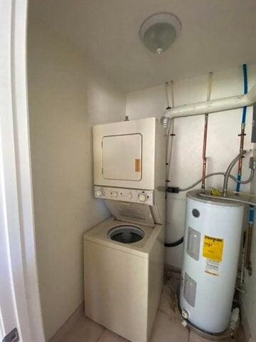 washroom with water heater, light tile patterned floors, and stacked washer / drying machine