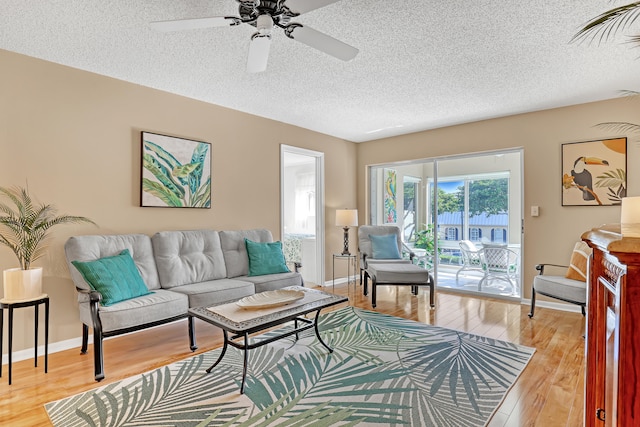 living room with a textured ceiling, light hardwood / wood-style flooring, and ceiling fan