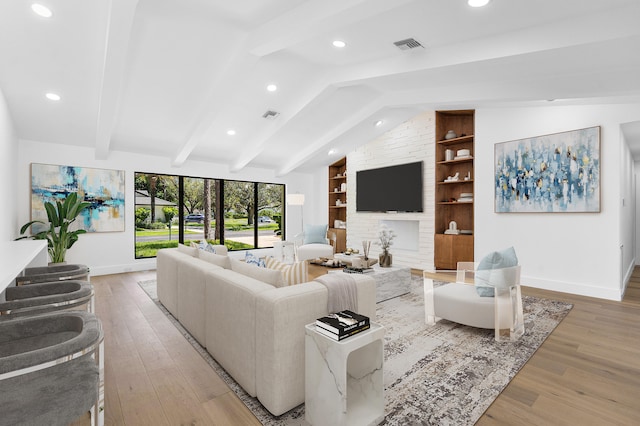 living room featuring lofted ceiling with beams, light wood-type flooring, and built in features