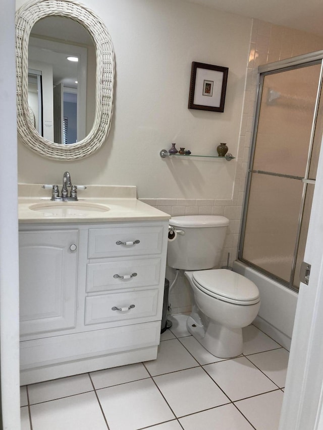 full bathroom with toilet, tile patterned flooring, tile walls, and shower / bath combination with glass door