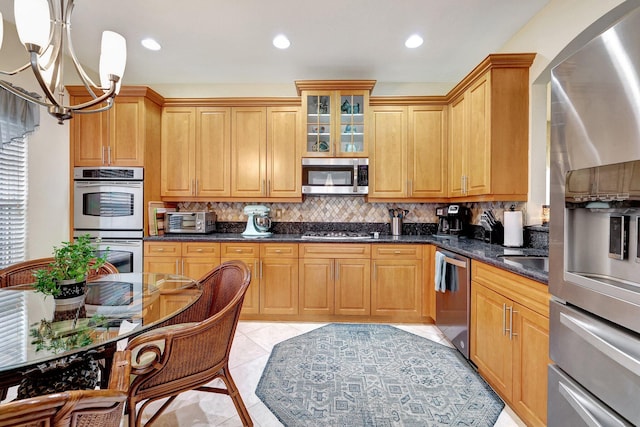 kitchen featuring hanging light fixtures, an inviting chandelier, dark stone countertops, light tile patterned floors, and appliances with stainless steel finishes