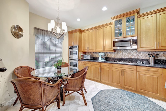 kitchen with appliances with stainless steel finishes, backsplash, light tile patterned floors, decorative light fixtures, and a notable chandelier