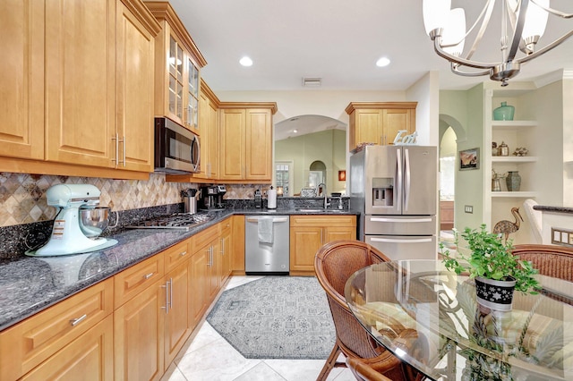 kitchen with sink, hanging light fixtures, light tile patterned floors, appliances with stainless steel finishes, and a notable chandelier