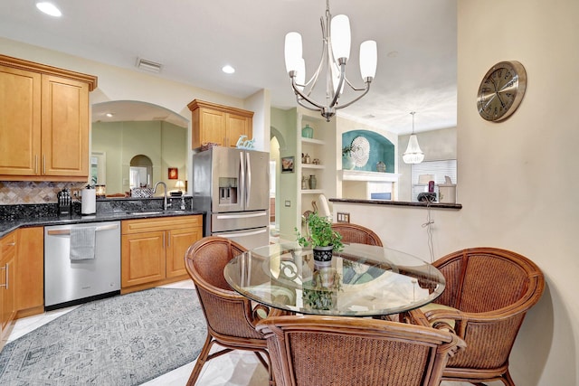 kitchen with pendant lighting, sink, decorative backsplash, appliances with stainless steel finishes, and a chandelier