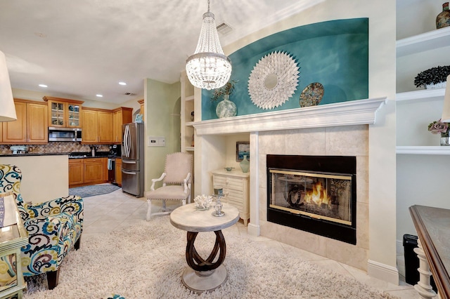 living room featuring a notable chandelier, light tile patterned floors, and a tile fireplace