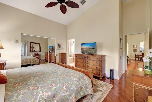 bedroom with high vaulted ceiling, ensuite bathroom, ceiling fan, wood-type flooring, and a closet