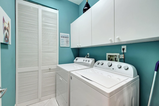 clothes washing area with cabinets, light tile patterned flooring, and washer and dryer