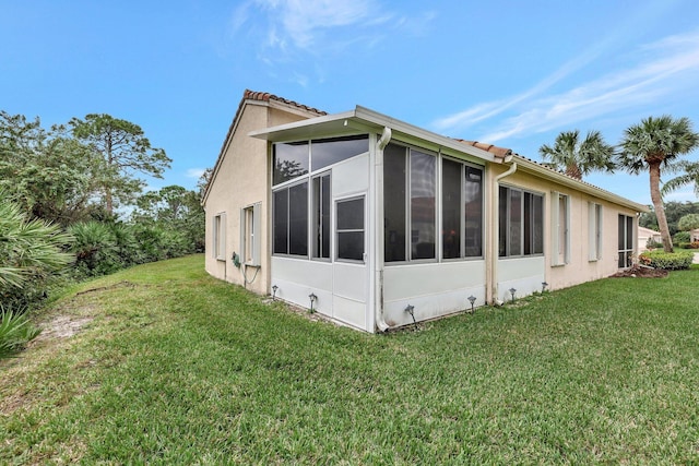 view of side of home with a lawn and a sunroom