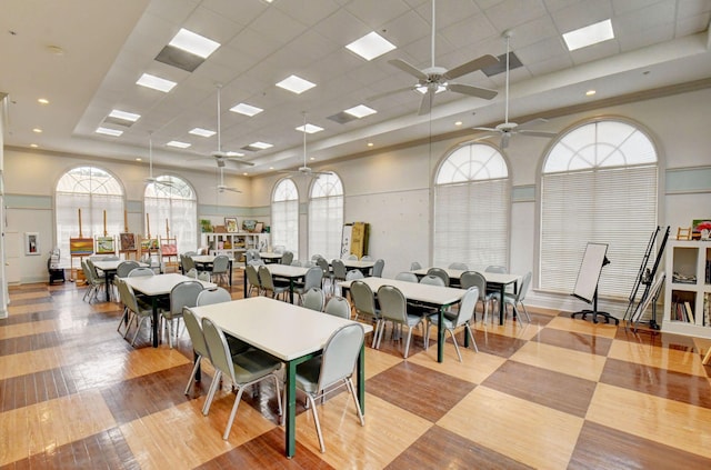 dining area featuring ceiling fan, a drop ceiling, light wood-type flooring, and a high ceiling