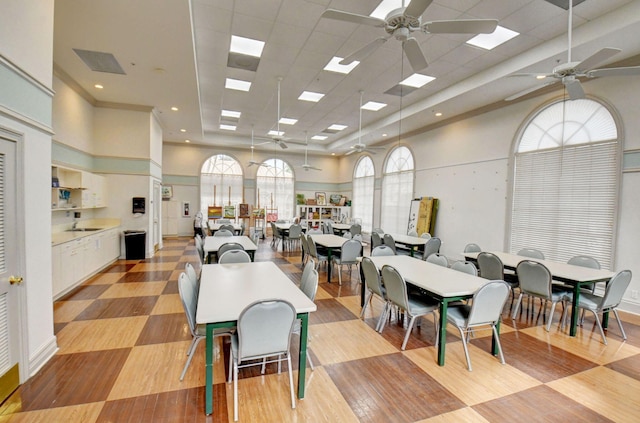 dining space featuring ceiling fan, light hardwood / wood-style floors, a drop ceiling, and a high ceiling