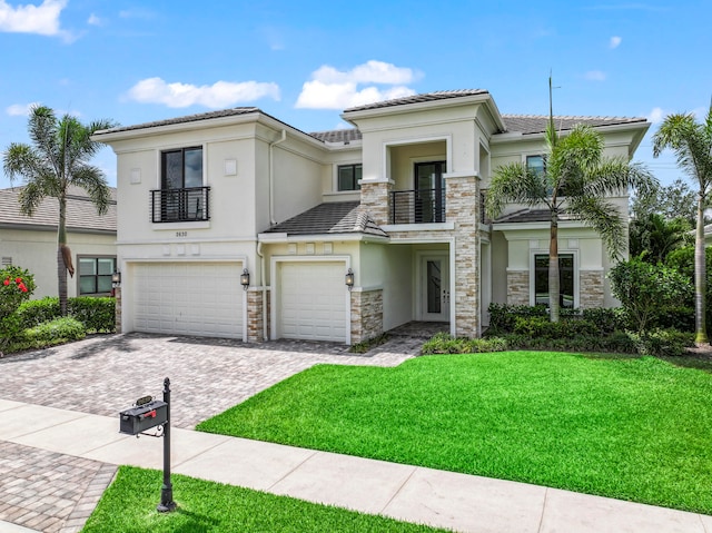 view of front facade featuring a balcony, a front yard, and a garage