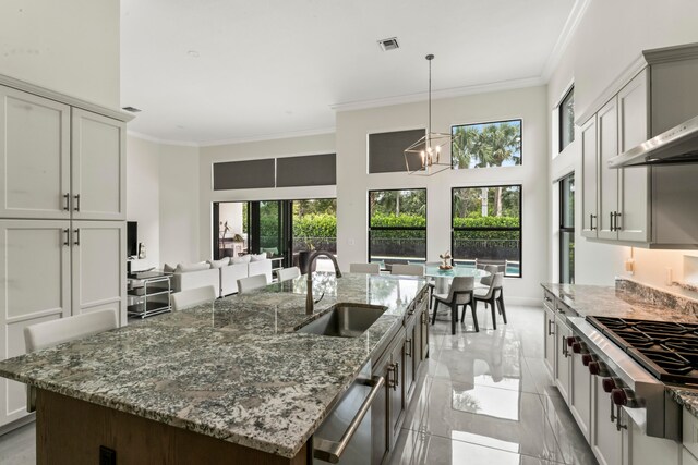 kitchen featuring ornamental molding, sink, stone counters, and a chandelier