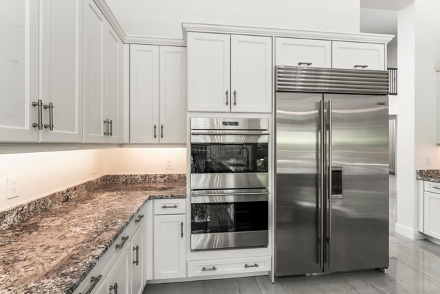 kitchen featuring dark stone countertops, white cabinetry, and appliances with stainless steel finishes