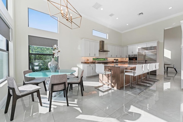 dining space featuring a chandelier, a towering ceiling, ornamental molding, and sink