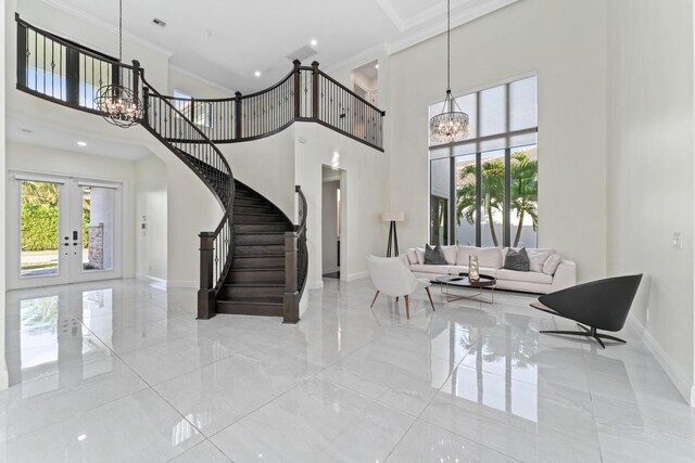 entrance foyer with french doors, a towering ceiling, a notable chandelier, and ornamental molding