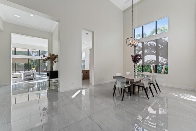 dining area featuring plenty of natural light, ornamental molding, and a high ceiling