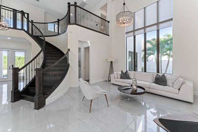 living room featuring a chandelier, french doors, a towering ceiling, and crown molding