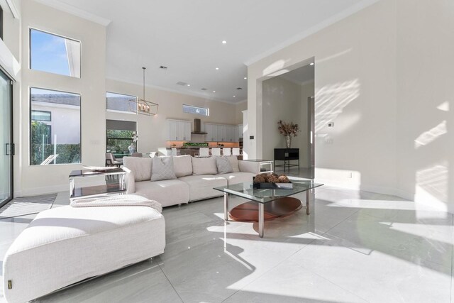 living room with plenty of natural light, a towering ceiling, an inviting chandelier, and ornamental molding