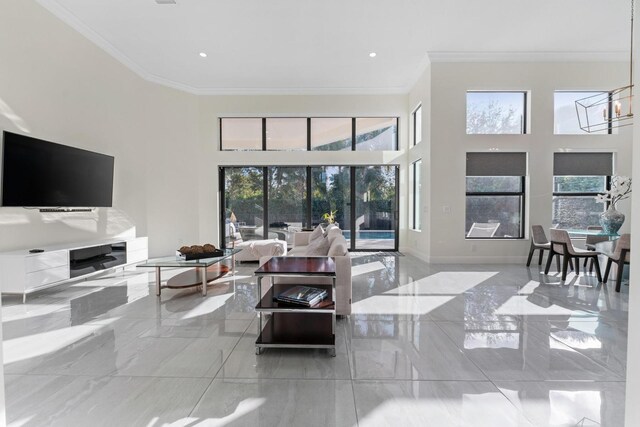 living room featuring crown molding, a high ceiling, and a chandelier